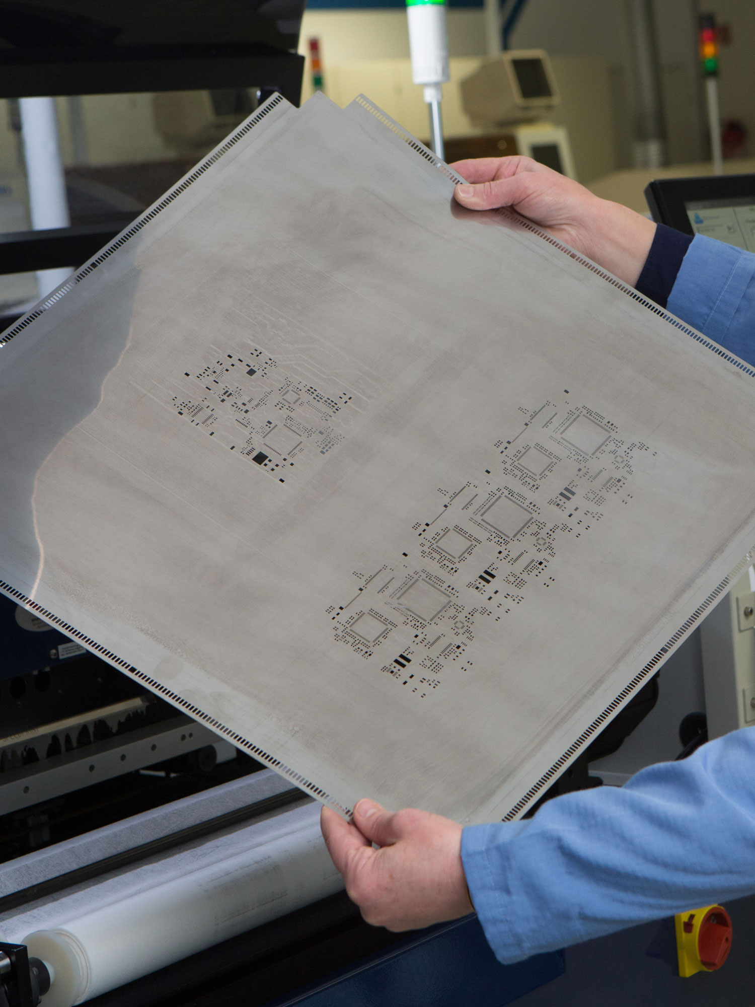 Zwei Hände halten ein Siebdrucksieb in der Produktion